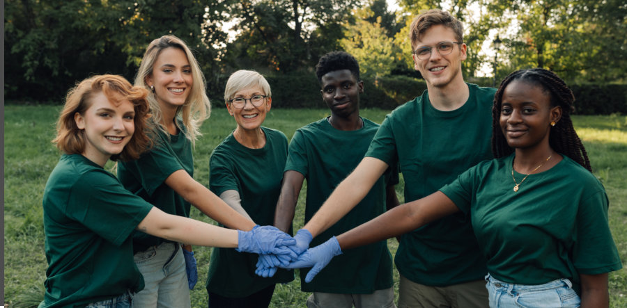 group of volunteers putting hands together wearing gloves in park
